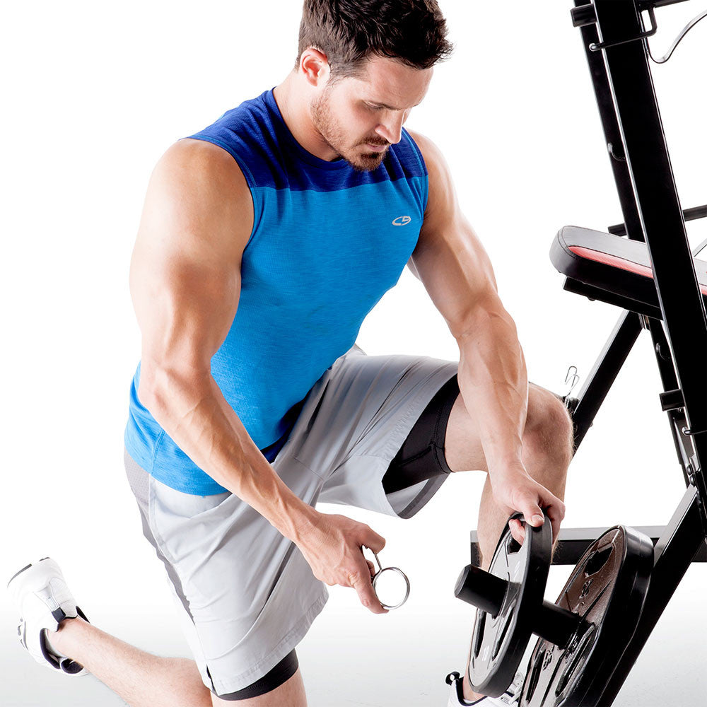 Placing Olympic plates on the storage posts of the Marcy Deluxe Olympic Weight Bench MKB-957