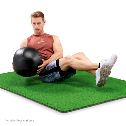 Man performing a Russian twist exercise holding a black medicine ball while seated on an assembled green Marcy Turf Puzzle Mat.